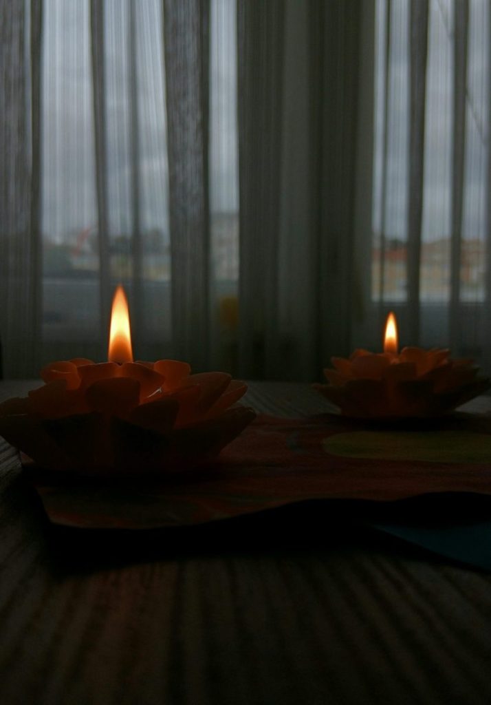 A serene image of decorative candles casting a warm glow indoors on a wooden table.